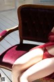 A woman in a red lingerie sitting on a chair.