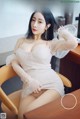 A woman in a white dress sitting on a chair.