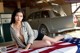 A woman sitting on top of an American flag next to a car.