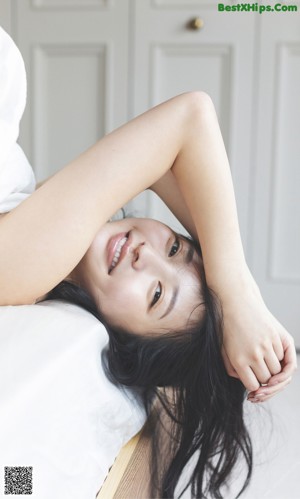 A woman laying on a bed with her hands behind her head.