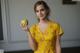 A woman in a yellow dress holding an apple.