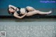 A woman in a black bikini laying on the edge of a pool.